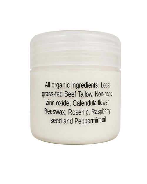 A white plastic jar with a ribbed screw-top lid, featuring black text on the front listing organic ingredients including beef tallow, zinc oxide, calendula, beeswax, rosehip, raspberry seed, and peppermint oil.
