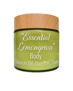 A jar of 'Essential Lemongrass' Body Balances Oil, Clairifies, and Tones, featuring a light wood-grain lid and a translucent olive-green glass jar with white text.