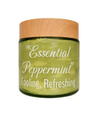 A green glass jar with a light wood lid, labeled 'Essential Peppermint Cooling, Refreshing' in white script, on a plain white background.