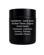 Black balm jar with herb-infused tallow ingredients label on white background.