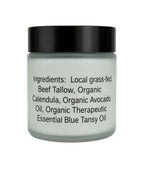 A jar of beef tallow body cream with a black lid and frosted glass container, showing the ingredients list on the front against a white background.